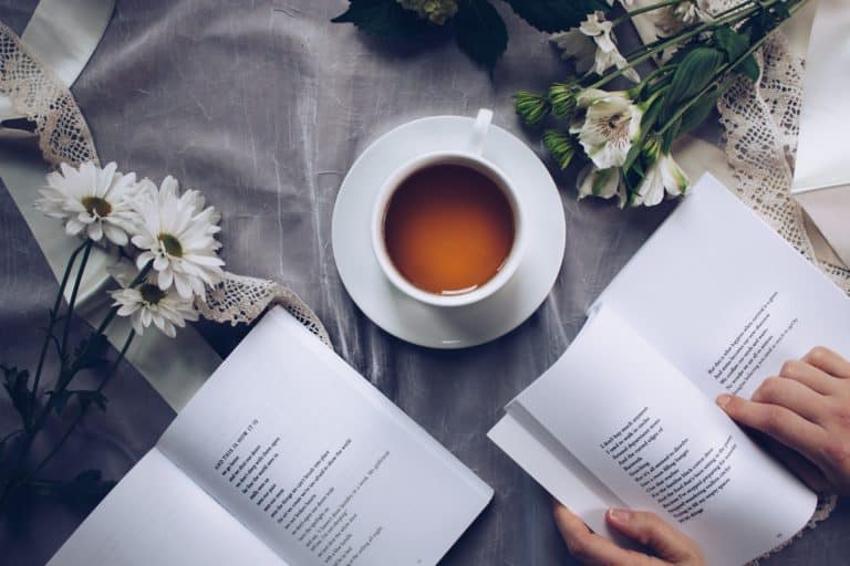 Reading a book on a blanket beside tea and flowers